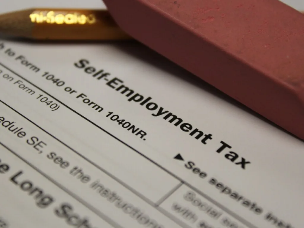 Close-up of the heading of IRS Schedule SE, Self-Employment Tax, with a pencil and eraser resting on the page